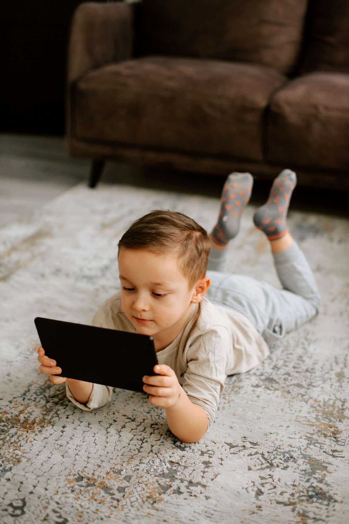 little boy laying on floor on ipad